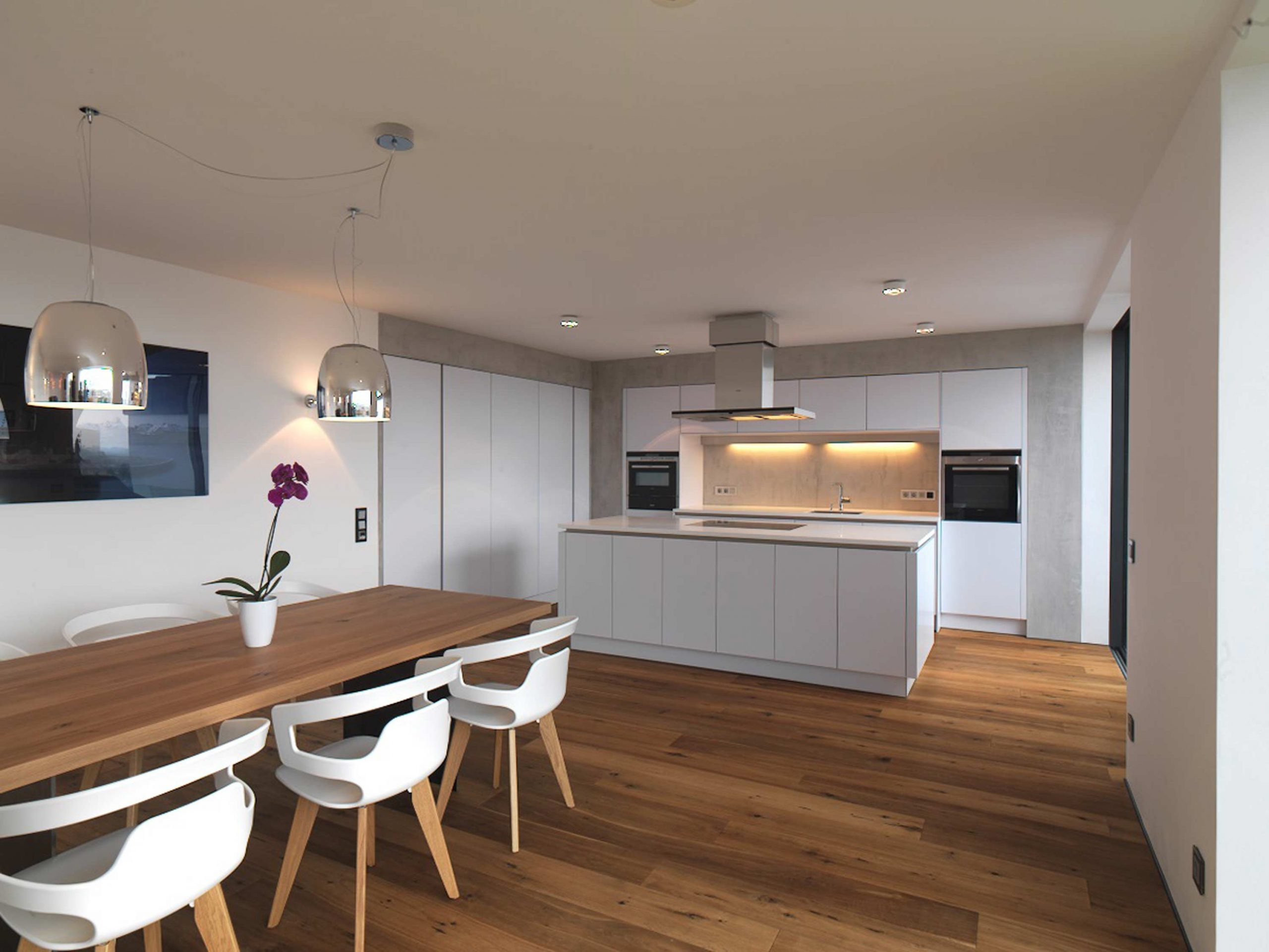 Der Ess- und Kochbereich mit separater Kochinsel und in die Wand integrierten Kuechenzeilen im Einfamilienhaus 