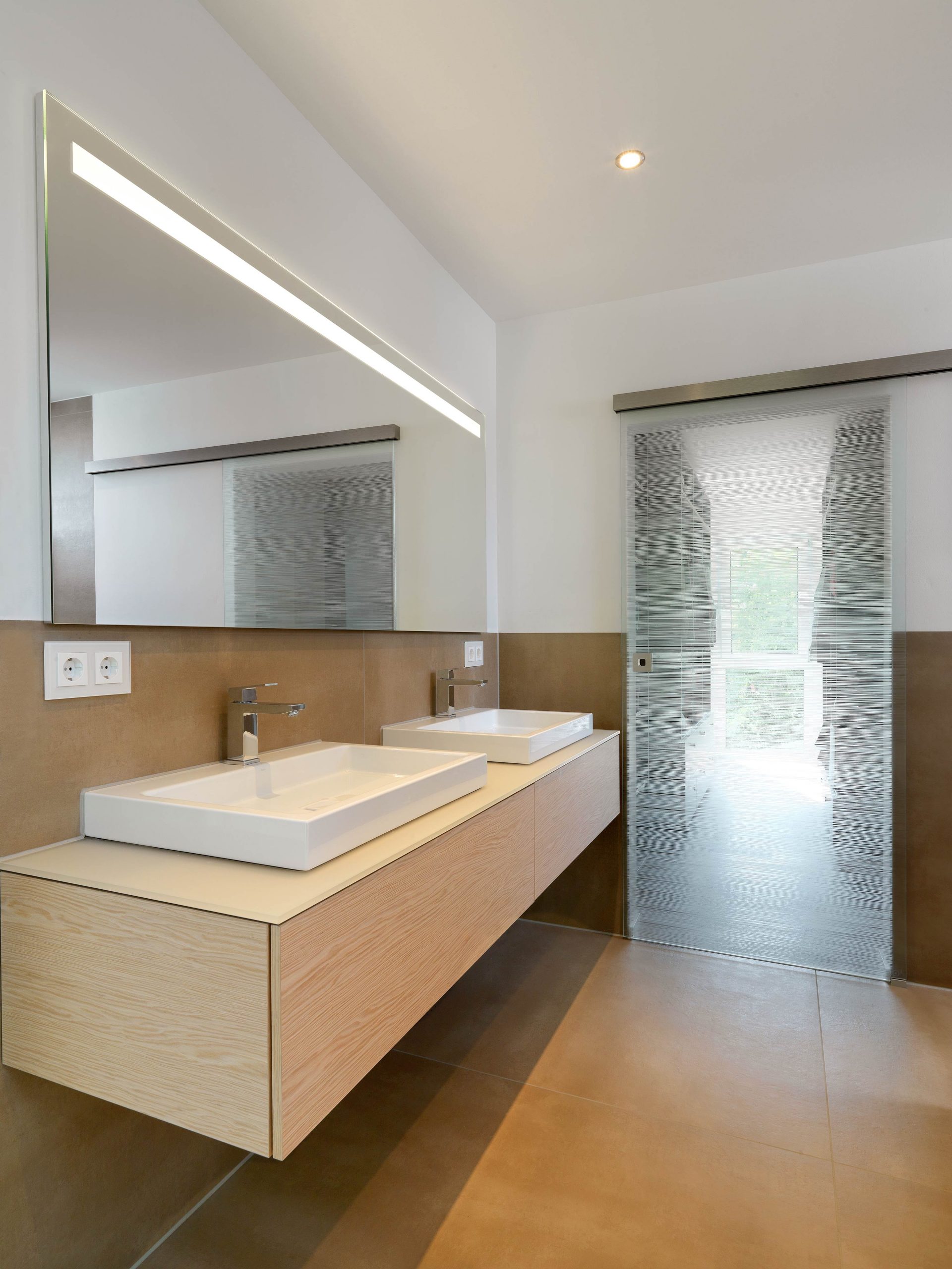 Der Waschtisch im Badezimmer der Eltern im Einfamilienhaus RSO mit Zugang zum begehbaren Kleiderschrank.